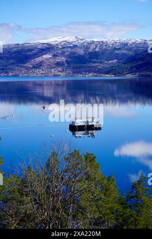 A Fish farm on the serene waters of a Norwegian fjord near Angvik, Norway Stock Photo