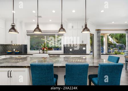 Modern open kitchen featuring two chairs and pendant lights above the island Stock Photo