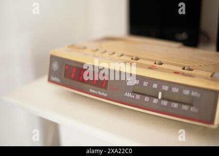 Red clock on wooden table beside microwave oven Stock Photo