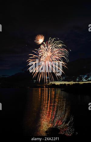 Fireworks lighting up the night sky over water Stock Photo