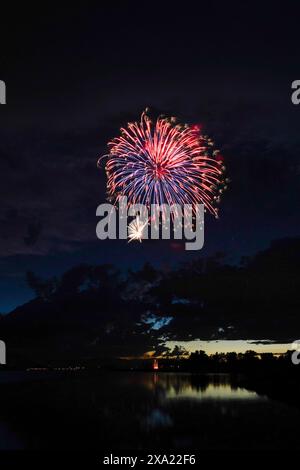 Fireworks lighting up the night sky over a waterfront Stock Photo