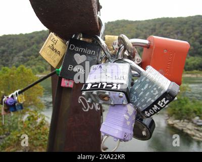 Many keys and padlocks hanging from a pole by the water Stock Photo