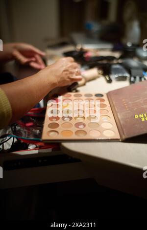 Makeup artist working with cosmetics on a counter next to a book Stock Photo