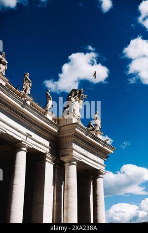 Multiple statues on a grand building under a blue sky and clouds Stock Photo