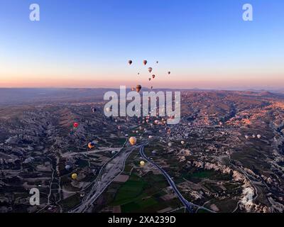 Colorful hot air balloons float above a town and road Stock Photo