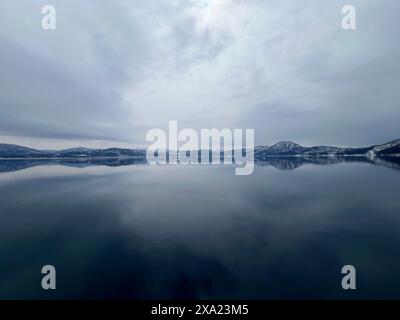 The beautiful view of Lake Tazawa with snowy mountains in the distance. Semboku, Akita, Japan Stock Photo