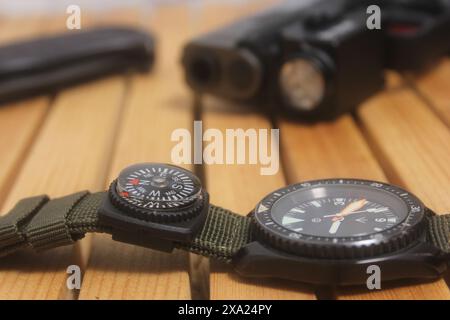 A wristwatch and a compass placed on a rustic wooden surface Stock Photo