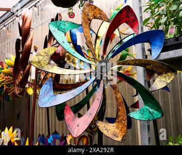 Closeup of an ornamental windmill with multicolored blades against a brown wall for sale at a market garden. Stock Photo