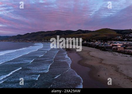 A picturesque coastal shore under a pink and red cloudy sky Stock Photo
