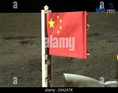 (240604) -- BEIJING, June 4, 2024 (Xinhua) -- A Chinese national flag carried by the lander of Chang'e-6 probe unfurls at the moon's far side, June 4, 2024. The ascender of China's Chang'e-6 probe lifted off from lunar surface on Tuesday morning, carrying samples collected from the moon's far side, an unprecedented feat in human lunar exploration history. The ascender has entered a preset orbit around the moon, said the China National Space Administration (CNSA). (CNSA/Handout via Xinhua) Stock Photo