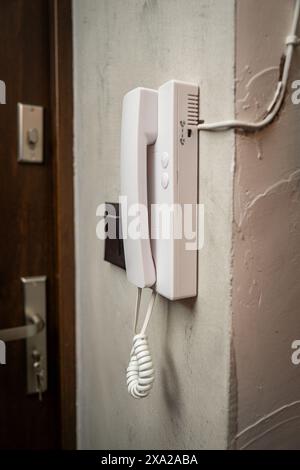 white intercom system mounted on a wall next to a door Stock Photo
