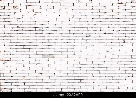 A white brick wall with peeling paint and rust spots Stock Photo
