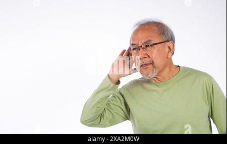 Portrait Asian old man with glasses and a beard listening to sound something, possibly engaged in Stock Photo