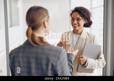 Happy diverse women office workers is distracted from work and talking in office during break Stock Photo
