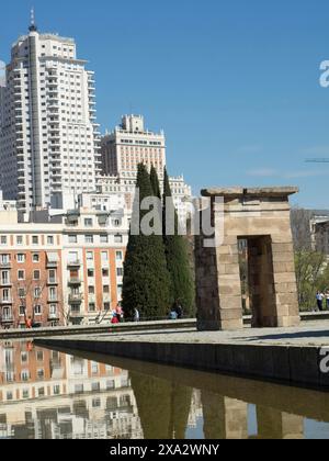 Ancient temple next to modern skyscrapers with reflections in the water under a clear sky, Madrid, Spain Stock Photo