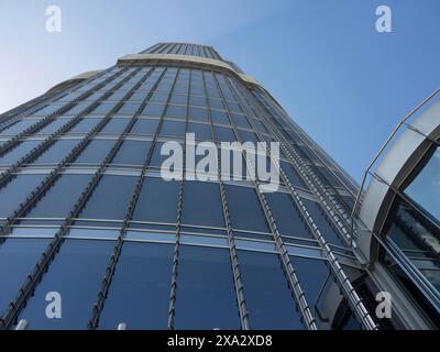 View upwards to a modern skyscraper with glass facade and a clear sky, dubai, arab emirates Stock Photo