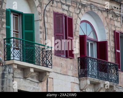 Detailed view of a building with green and red shutters and balconies in the old architectural style, Valetta, Malta Stock Photo