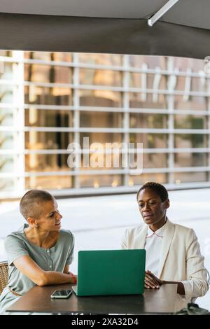 Two businesswomen working on a laptop at a table Stock Photo