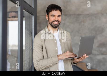 Smiling Man Using Laptop in Modern Office Building Stock Photo