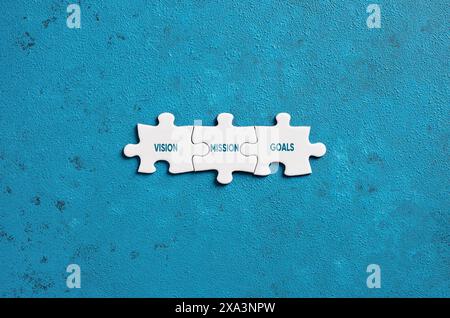 The business strategy words vision, mission and goals on puzzle pieces on blue background. Stock Photo