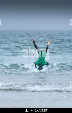 An enthusiastic surfer attempting a headstand on his surfboard in the Sand Bandit Showdown surfing competition at Gt Western Great Western Beach in Ne Stock Photo