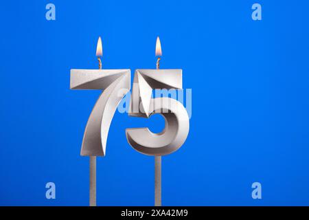 Birthday candle number 75 - Celebration card on blue background Stock Photo