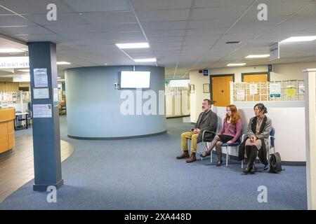Three people waiting in a modern reception area of a medical practice Stock Photo