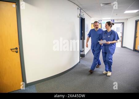 Two healthcare workers walking in a hospital corridor, medical practice UK Stock Photo