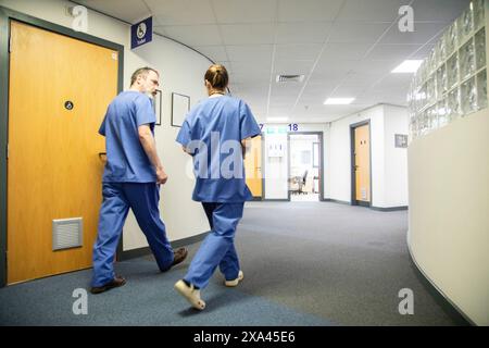 Two healthcare workers walking in a hospital corridor, medical practice UK Stock Photo