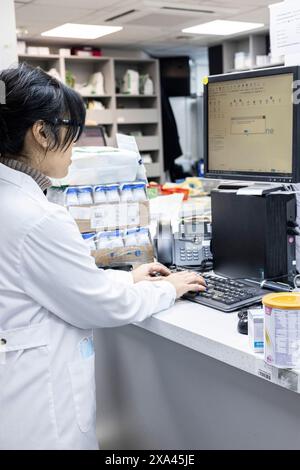 Scientist works at a computer in a lab and dispatch area of a medical practice Stock Photo