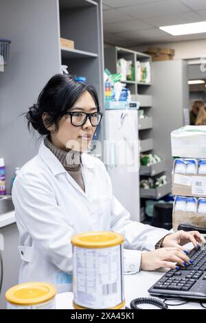Scientist works at a computer in a lab and dispatch area of a medical practice Stock Photo