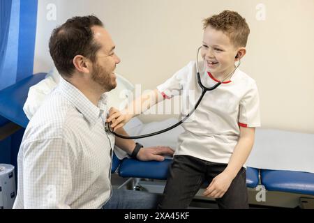 Boy using stethoscope on doctor for fun Stock Photo
