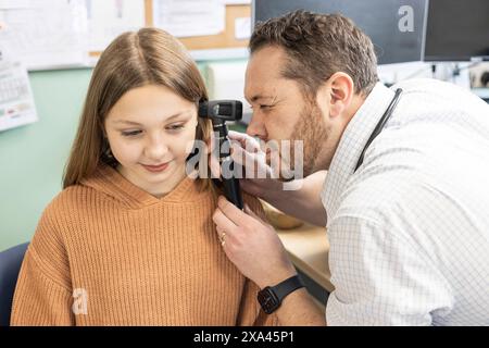 Doctor examining young girl's ear with an otoscope Stock Photo