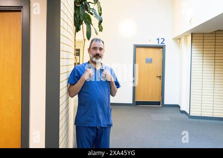 Doctor in blue scrubs standing in hospital corridor Stock Photo