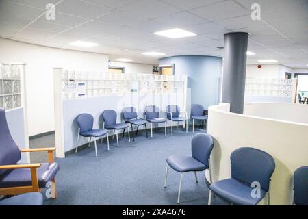 Empty waiting room with blue chairs and wall-mounted bulletin boards of a medical practice Stock Photo