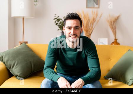 Man smiling while sitting on a yellow couch Stock Photo