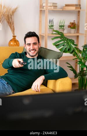 Man relaxing on a couch with a remote control in hand. Stock Photo