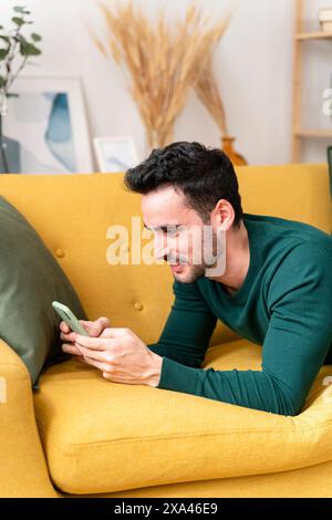 Man using smartphone on yellow sofa Stock Photo