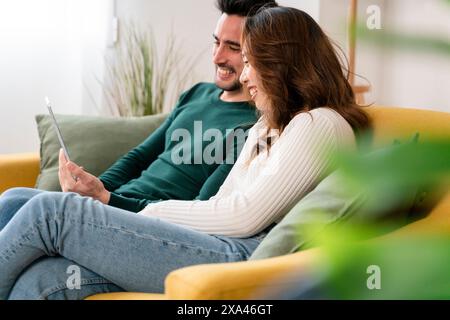 Couple laughing on a couch with a tablet Stock Photo