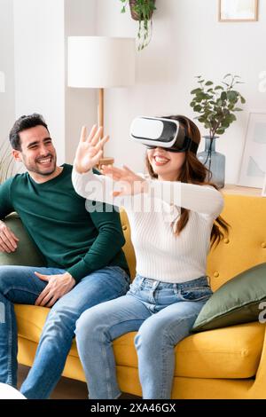 Woman uses VR headset with man on couch Stock Photo