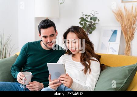 Couple enjoying time together with a tablet on a couch Stock Photo