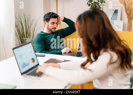 Two professionals discussing work at a laptop in a bright office. Stock Photo