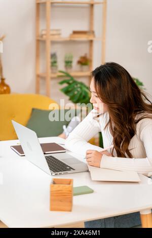 Woman focused on her laptop at a bright home office Stock Photo