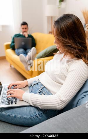 Woman working on laptop with man in background Stock Photo