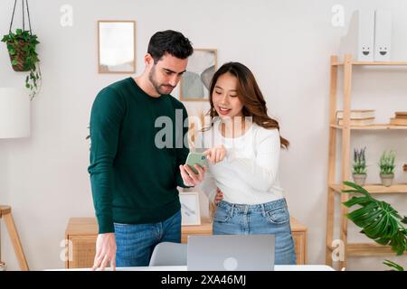 Two people looking at a smartphone together in a modern office Stock Photo