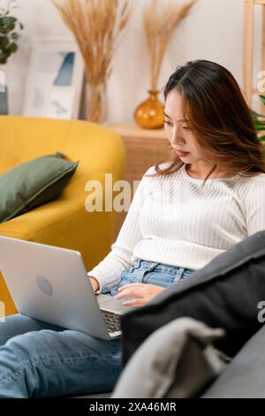 Woman working on laptop while sitting on a couch Stock Photo