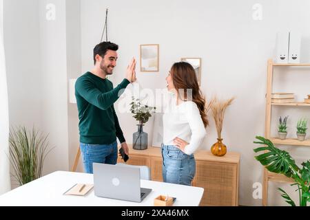 Two individuals high-fiving in a modern office. Stock Photo