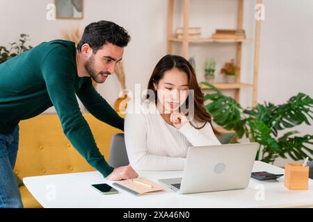 Two professionals collaborating over a laptop in an office setting. Stock Photo