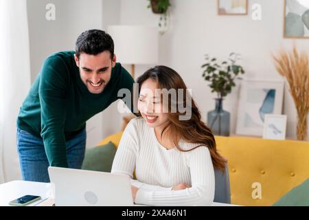 Two people smiling and looking at a laptop screen. Stock Photo