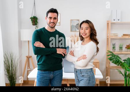 Confident man and woman posing with arms crossed in a modern office. Stock Photo